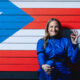 Deborah Martorell con la bandera de Piuerto Rico de fondo